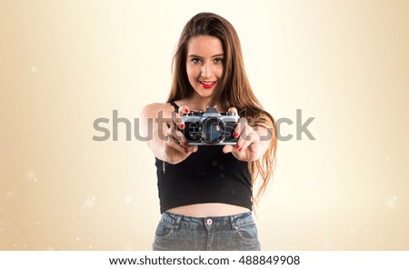 Young girl holding a camera over ocher background