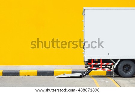 transportation and vehicle concept - Delivery truck car parking at footpath with yellow wall background and space for text. Use for logistics car artwork