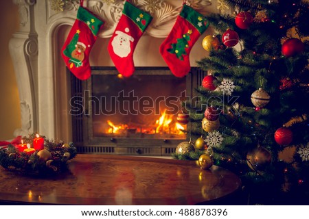 Toned image of empty wooden table in front of decorated fireplace and Christmas tree. Place for text. Suitable for Christmas background.