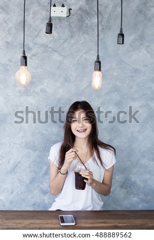Young beautiful woman offers cup of coffee gray background