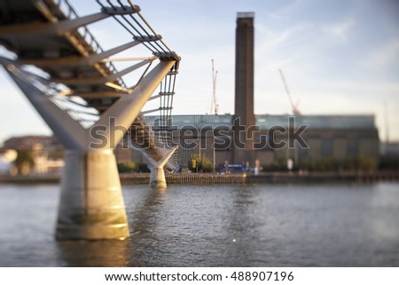 Tilt Shift image of the iconic Millennium Bridge spanning the River Thames under blue skies with the Tate Modern