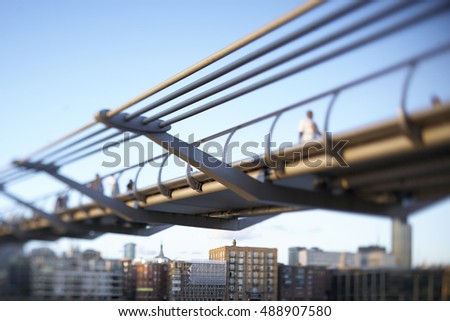 Tilt Shift image of the iconic Millennium Bridge spanning the River Thames under blue skies