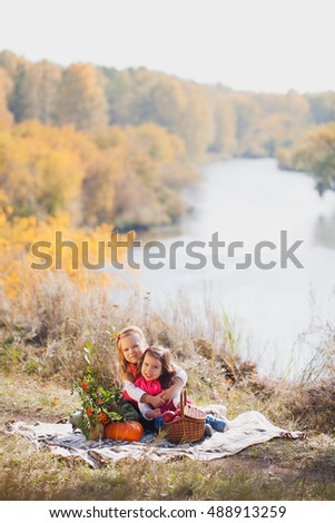 Two sisters on a picnic on a sunny autumn day with a basket of apples and pumpkins. Harvesting.