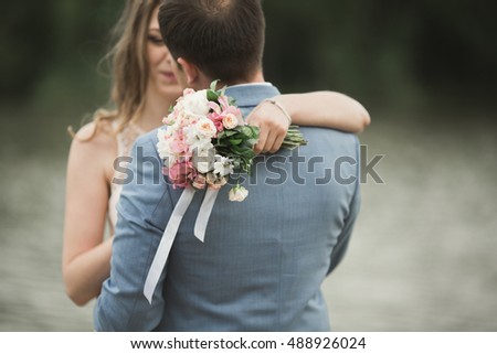 Beautiful wedding couple, bride,groom kissing and posing on the bridge near lake