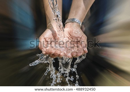Spring water flows from the pipe into the hands with motion blur