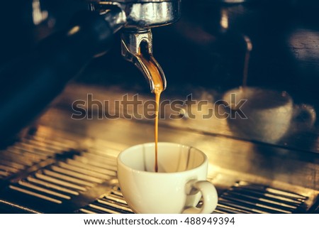 Coffee made in professional espresso machine pouring into a cup. Toned picture