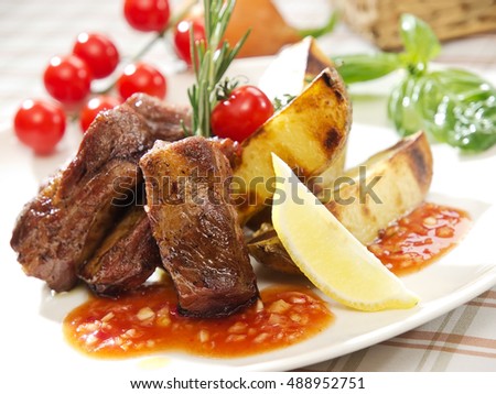 Grilled ribs in spicy sauce, french fries and tomatoes. Close up photo