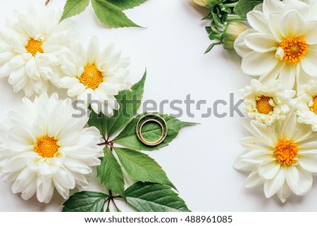 wedding rings and white dahlias on a light background
