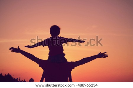 father and son having fun on sunset sky