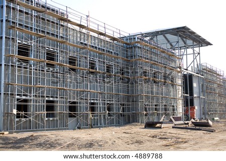 This commercial building has tilt-up concrete walls surfaced with metal studs and a sheath to be applied by workmen on the scaffolding surrounding the building
