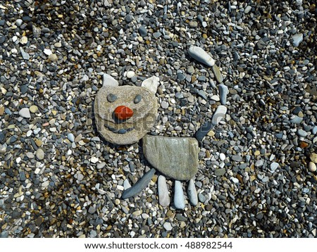 A very nice figure of a kitten made of small stones on the pebble background.