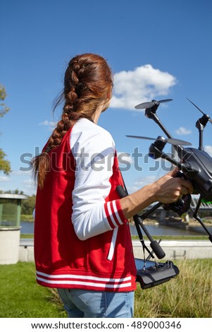 A woman is standing and holding drone over sky
