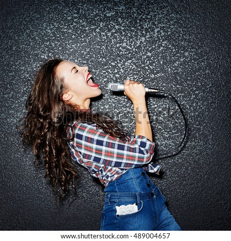 Woman singing with microphone Royalty-Free Stock Photo #489004657