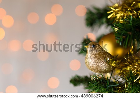 Festive Christmas close up of tree decorated with gold glitter robin, tinsel and bauble. Bokeh copy space.