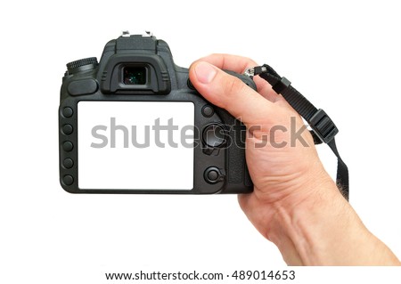 SLR digital camera in human hand on a white background with a white screen. DSLR camera back sibe in hand. Royalty-Free Stock Photo #489014653