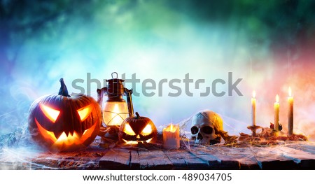 Halloween - Lanterns And Pumpkins On Wooden Table In A Haunted Forest
