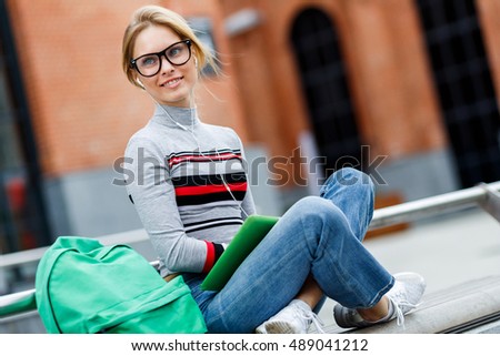 Girl in glasses and headphones sitting on street