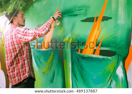 The artist draws graffiti on a fence.