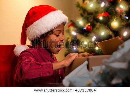 Joyful black boy opens present. Happy child opening Christmas present. Anticipation was worth it. One of many holiday miracles.