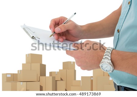 Delivery man writing on clipboard against cardboard boxes over white background
