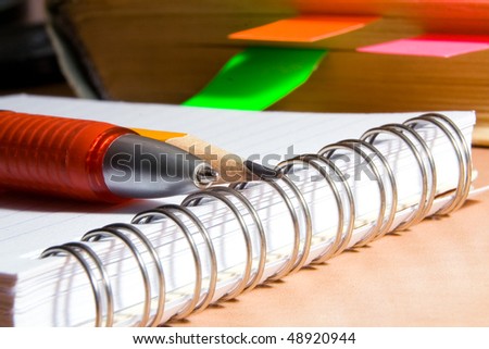 Notebook for notes, the book, the pen, a pencil on a desktop
