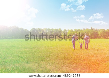 Happy family enjoying life together walking through the meadow