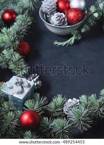 Christmas tree branches with baubles on dark black background. Copy space. Vertical image