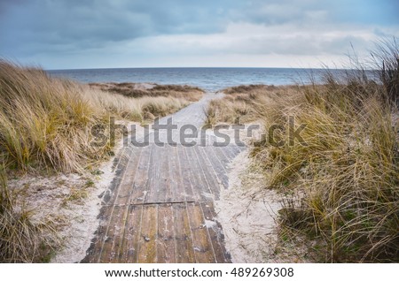 Beach of baltic sea in cold days. Original Wallpaper with soft colors. Coastal scenery with sandy beach, dunes with marram grass and rough sea on winter day. Royalty-Free Stock Photo #489269308