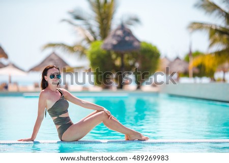 Beautiful young woman relaxing in infiniti pool at luxury hotel