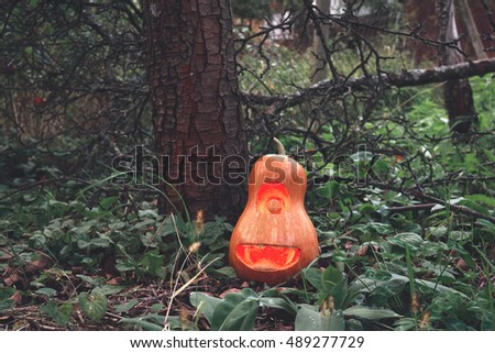 Halloween pumpkin minion in the woods on the grass near the tree