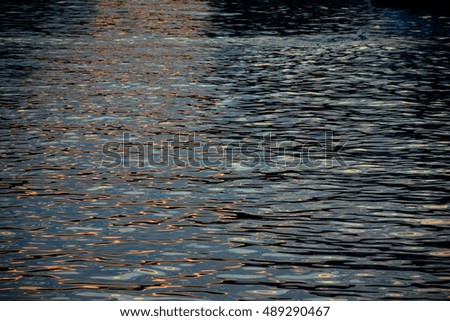 Detailed sea texture at sunset with sun reflection passing over
