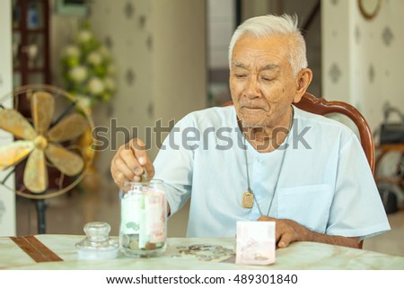 senior man counting money with glass bank