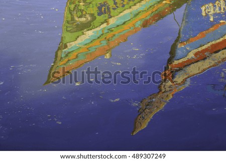 shadow of wooden fishing boat floating on the colourful water 