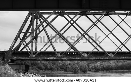 A black and white landscape photograph of a railroad bridge on the American countryside.