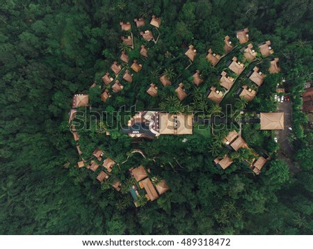 Aerial view of luxury resort in rain forest surrounded by trees. Hotel with cottages and swimming pool.