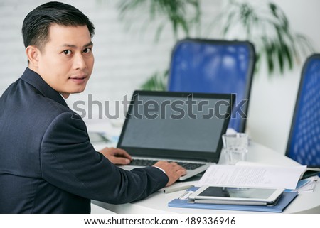 Vietnamese businessman busy with work on laptop at table