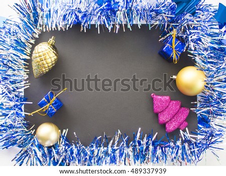 Christmas or New Year flat composition. Blue sparkling ribbon wreath frame. Fir tree, pine, ball and gift. Black paper with blank page. Season image for greeting card or banner. Festive background