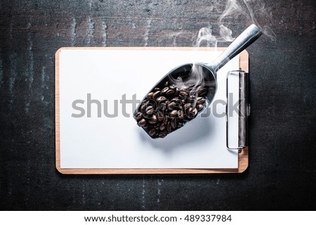 Blank clipboard with coffee bean on black stone background