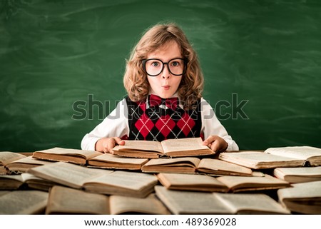 School child in class. Happy kid against green blackboard. Education concept