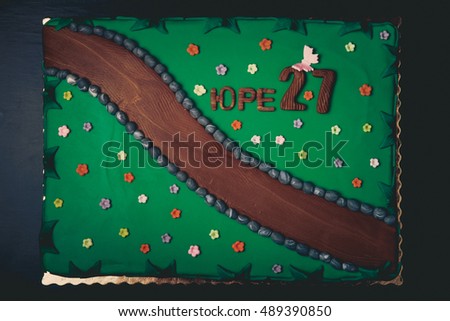 Birthday cake with inscription "Yura 27" on green background. Toned.