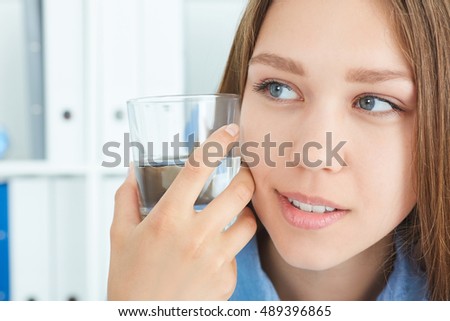 Beautiful passion smiling girl holding a glass with water in the office background..
