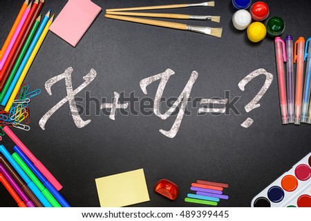 The title x plus y on the chalkboard (school board) and school, office supplies (paints, pencils, brushes, paper clips).