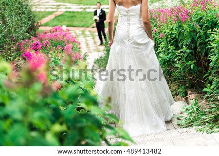 A picture of a young bride coming down the stairway to her widely smiling groom, pink flowers all around them