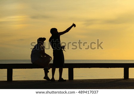 silhouette of lovers take a photo on the beach after sunrise