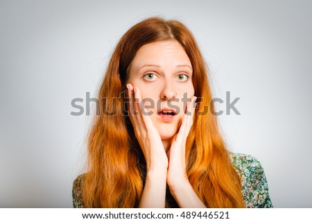 Shocked red-haired young woman frightened