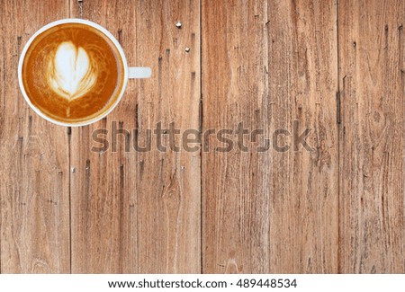 Top view of a coffee with heart pattern in a white cup on wooden background, latte art
