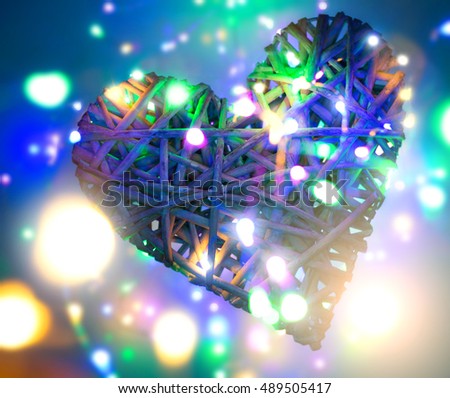 (osier, sallow, vine) braided on a frame in the form of hearts on a background of defocused multicolored LED light