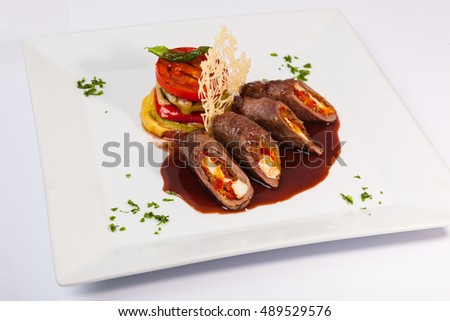 meat rolls with sauce and vegetables with cheese on plate