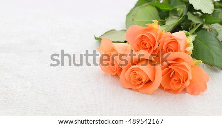 Beautiful orange roses in bouquet closed up on material to holiday gift or wedding present.
