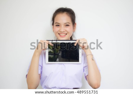 Portrait of thai high school student uniform beautiful girl using her tablet. text on shirt, logo Satriwithaya school in bangkok thailand